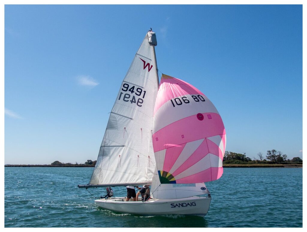 A Wayfarer sailing dinghy with spinnaker up sailing on a sunny day